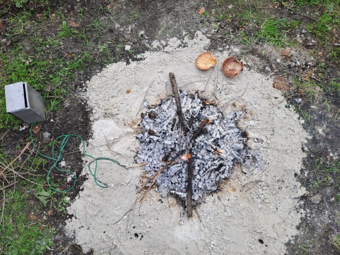 An overhead image of a sandy circle with a burning area in the middle.