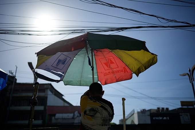 A man in Manila opens an umbrella to block the sun.