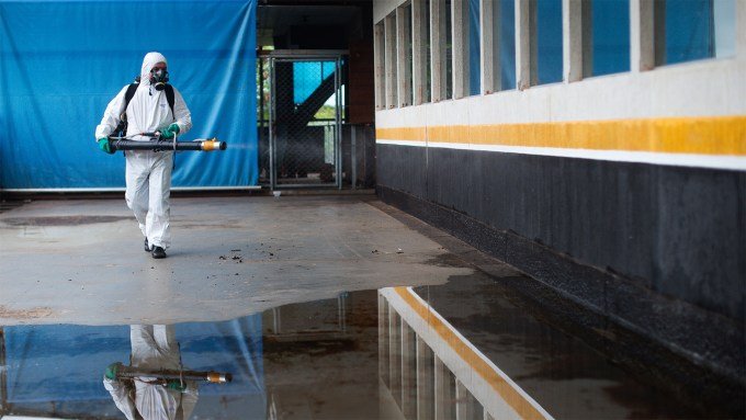 A person wearing personal protective gear sprays insecticide at a mall to kill mosquitoes.