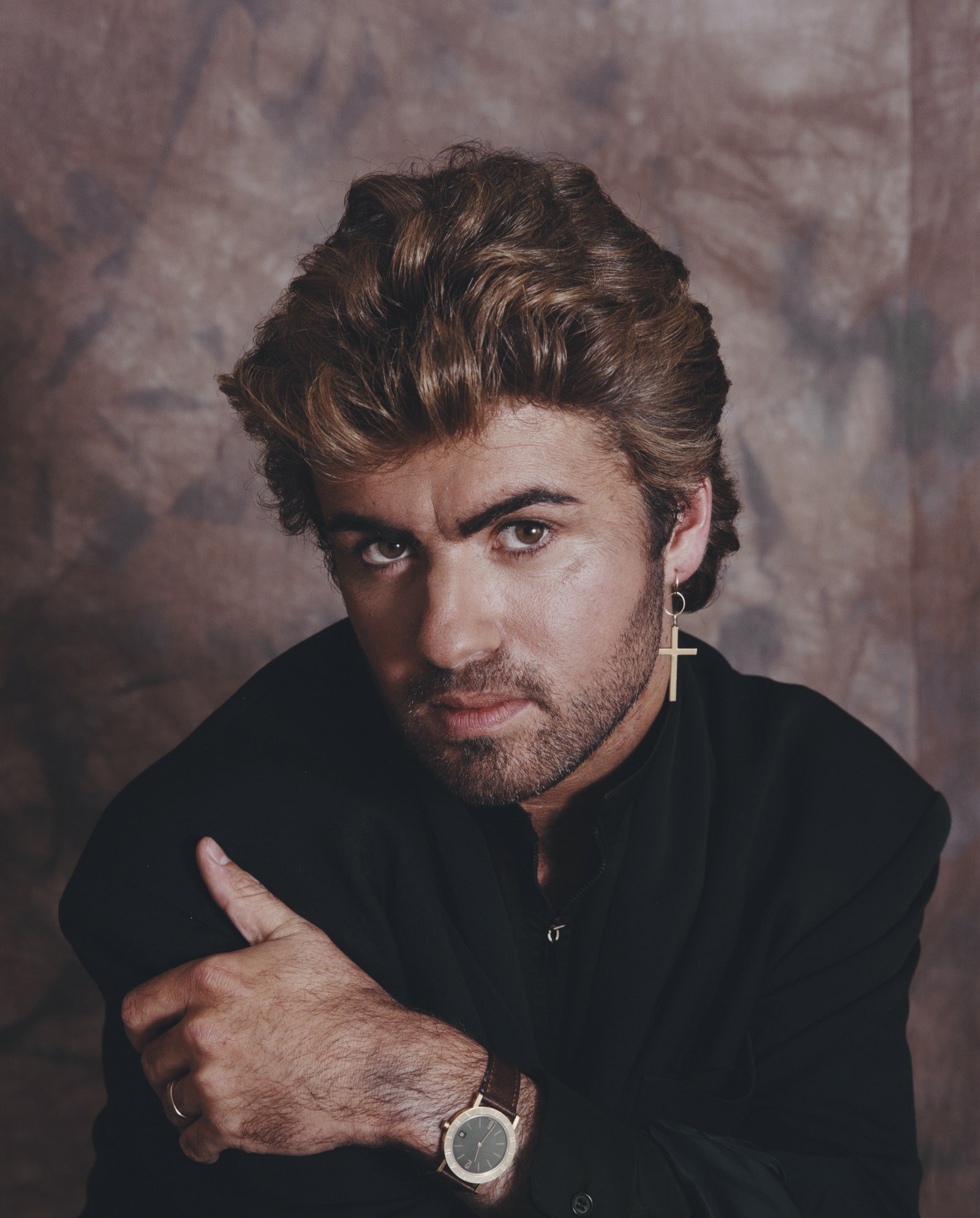 Image may contain George Michael Face Head Person Photography Portrait Body Part Finger Hand Adult and Wristwatch